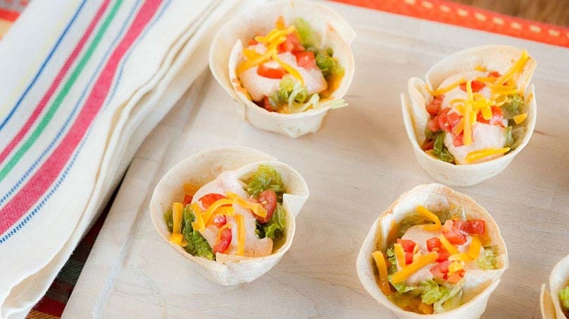 Mini Taco Tortilla Cups on baking sheet, striped kitchen towel