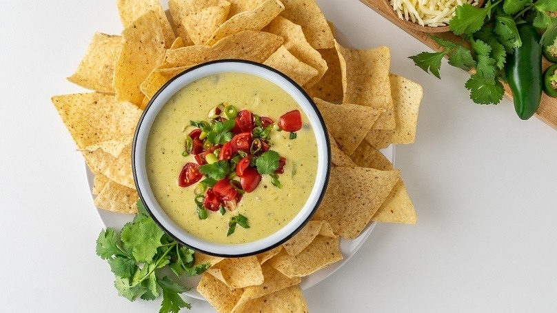 Three Cheese Cauliflower Queso, tortilla chips, cilantro, choppeed peppers