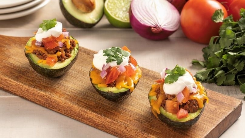 Taco Stuffed Avocados on cutting board, plates, cut avocado and red onions, tomatoes, cilantro