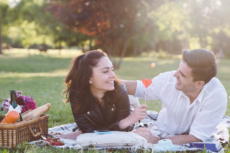 Young couple sharing a valentine's picnic in the park.