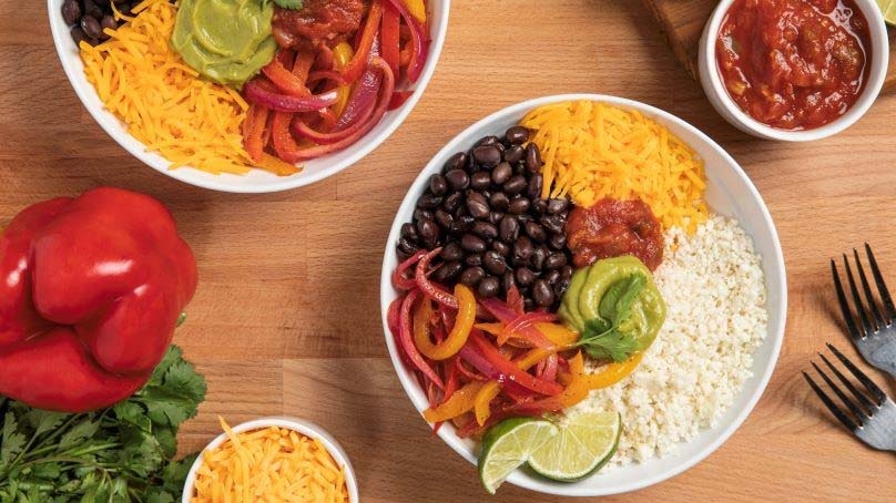 Low Carb Cauliflower Burrito Bowls, bell pepper, garnish, shredded cheese, salsa, wood table