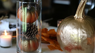 vase filled with small pumpkins and pine cones