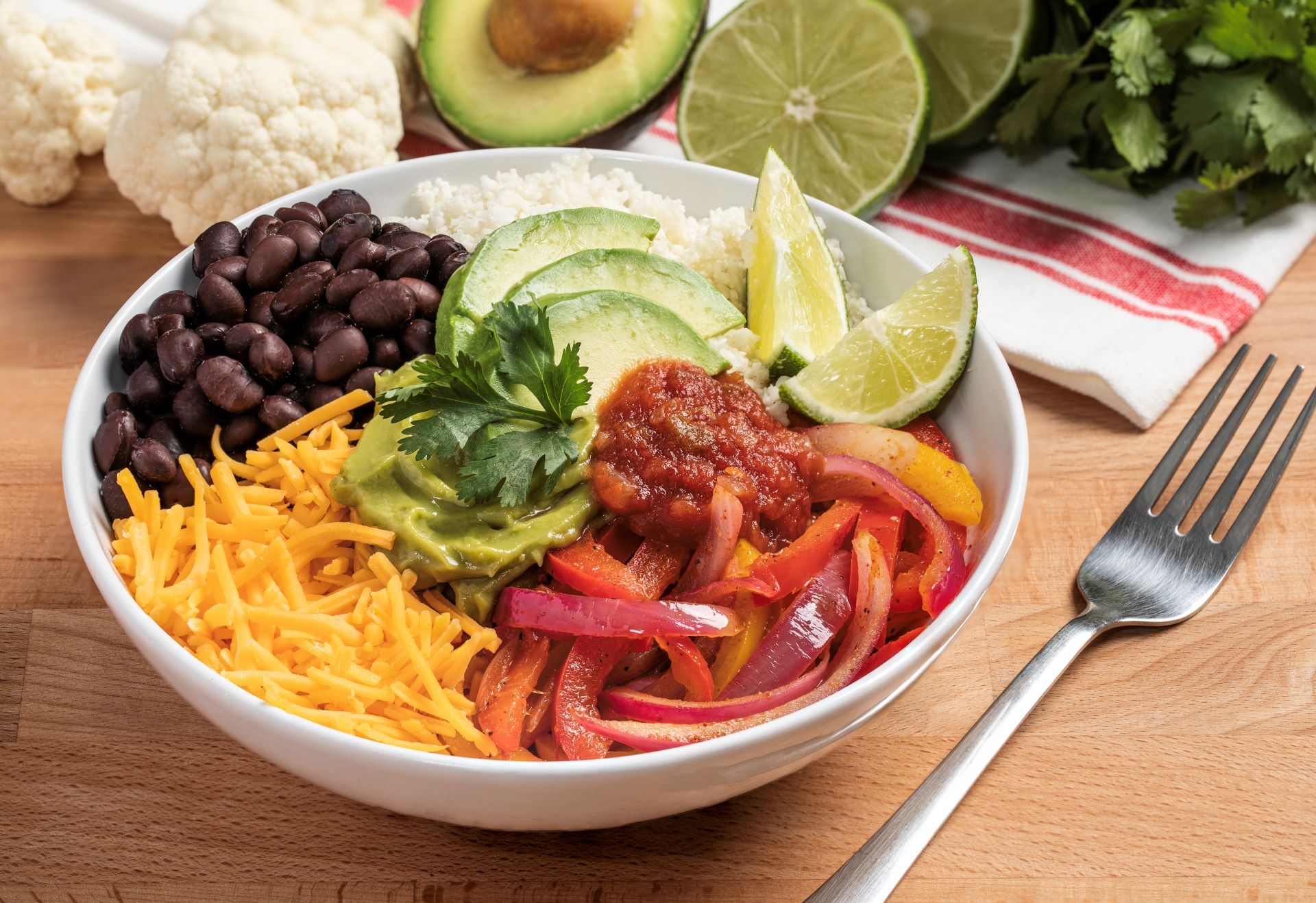 Cauliflower Rice Burrito Bowl, miscellaneous ingredients, fork, kitchen towel, wood table