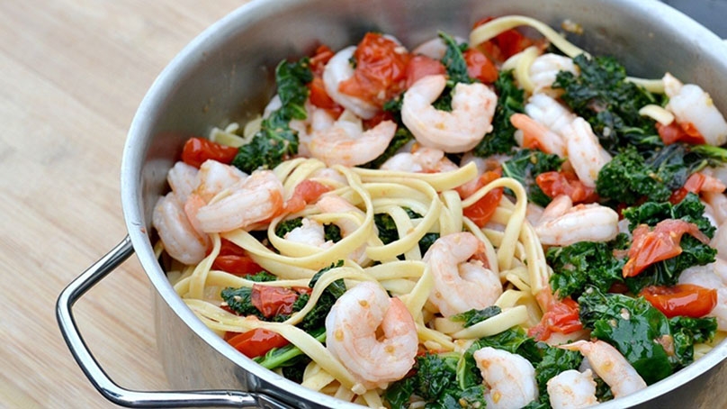 Garlic Butter Shrimp with Kale in stainless steel pot, light wood countertop