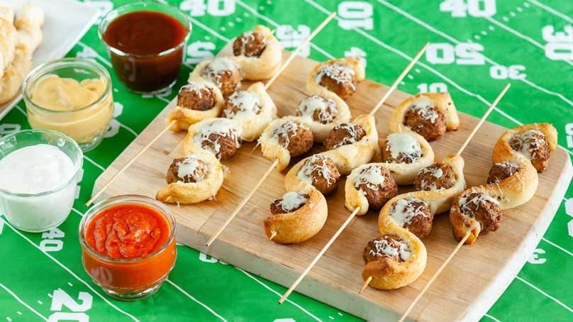 Cheesy Meatball Subs on a Stick Game Day Snack, cuting board, football field tablecloth, dipping sauces