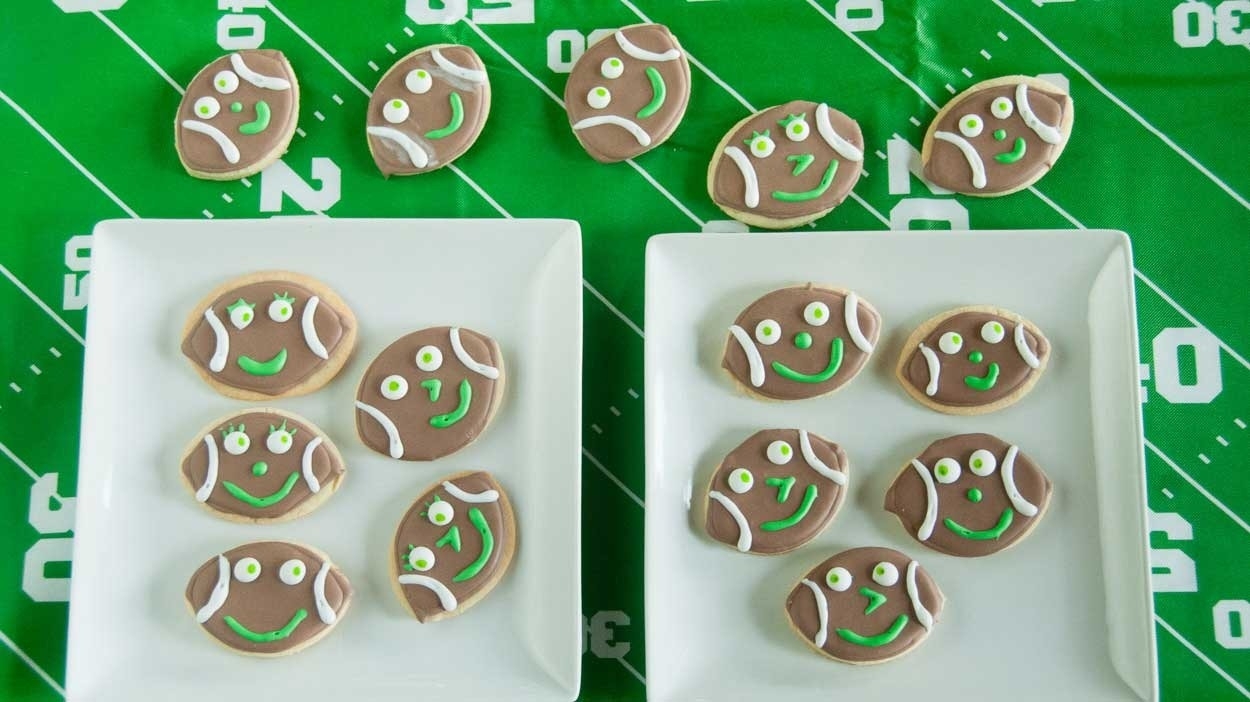 Football shaped cookies with smiley faces, square serving plates, football field table cloth