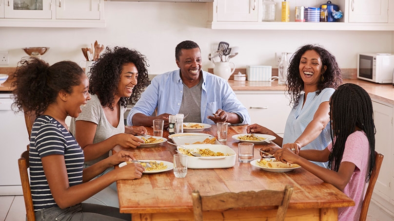 Happy family sharing a meal around the kitchen table, Mother, Father, Three daughters