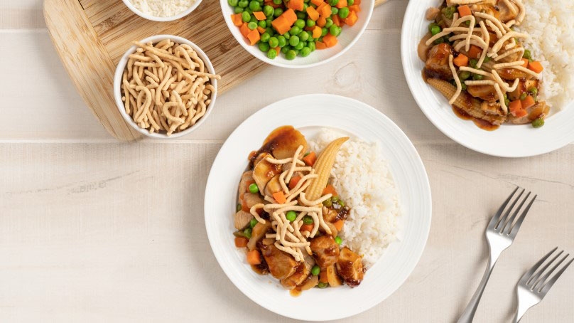 Teriyaki Chicken Stir Fry with rice, white plkates, forks, cutting board, noodle, mixed veggies, rice