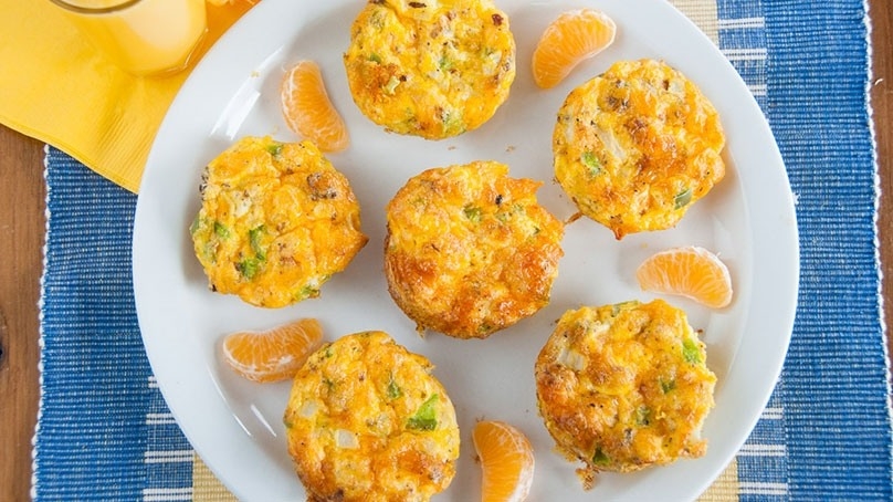 Egg Muffins on white plate, blue placemat, yellow napkin, wood table