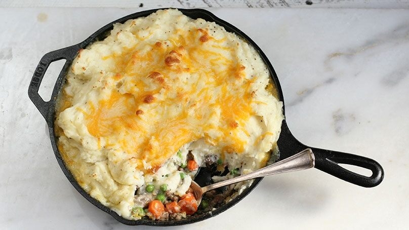 Skillet Shepherd’s Pie, cast-iron skillet, spoon, marble cutting board, wood table