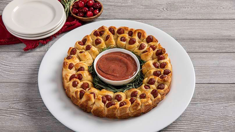 Pigs-in-a-blanket chritmas wreath on table